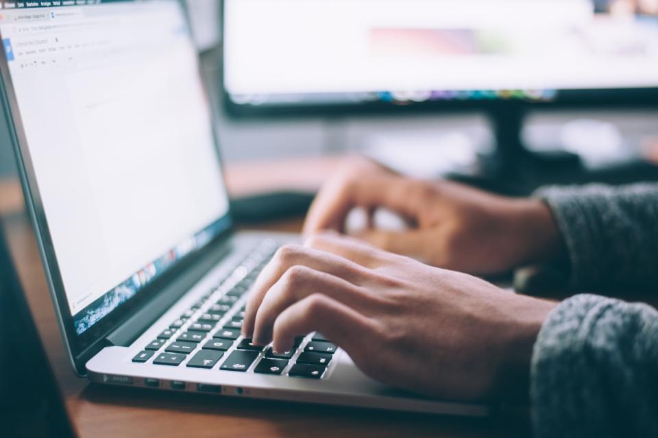 A woman's hands rest on a laptop keyboard