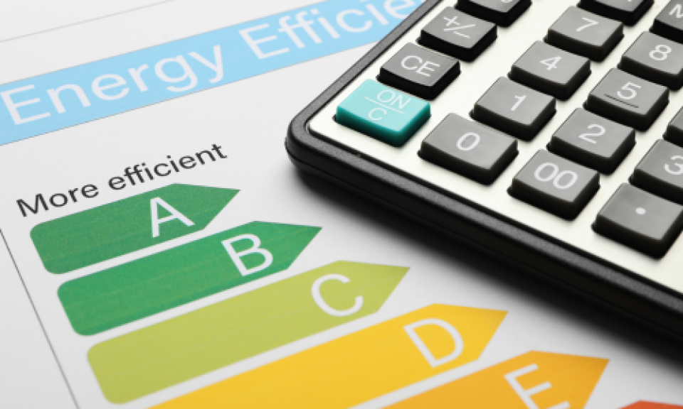 A calculator next to energy ratings, symbolising calculating energy efficiency