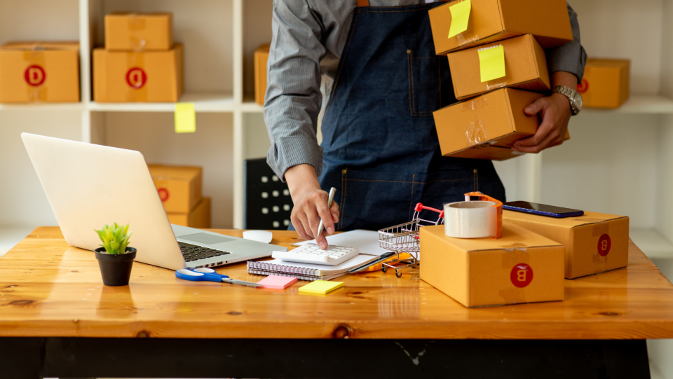 Someone packing boxes and at their laptop, symbolising a business