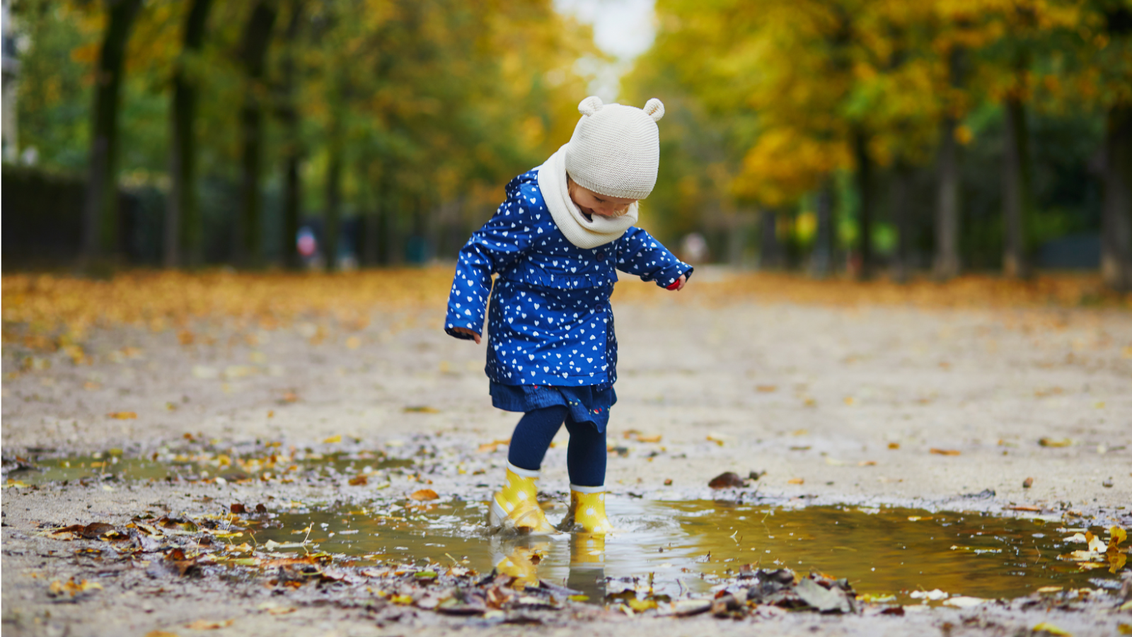 child wearing wellies and playing in a puddle 